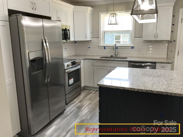 kitchen featuring a sink, stainless steel appliances, light wood-type flooring, backsplash, and pendant lighting
