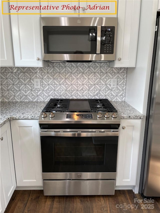 kitchen with white cabinets, backsplash, appliances with stainless steel finishes, and light stone counters