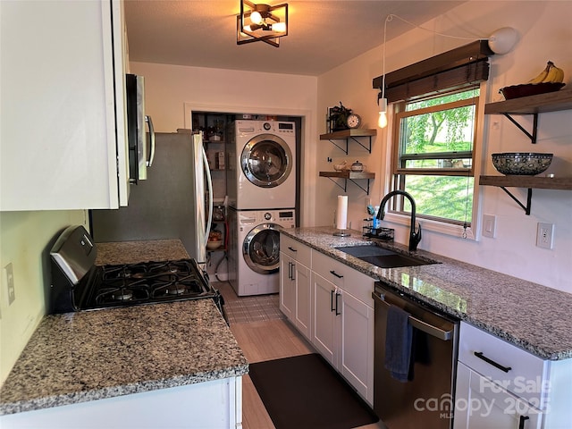 kitchen featuring stacked washer and dryer, open shelves, appliances with stainless steel finishes, and a sink