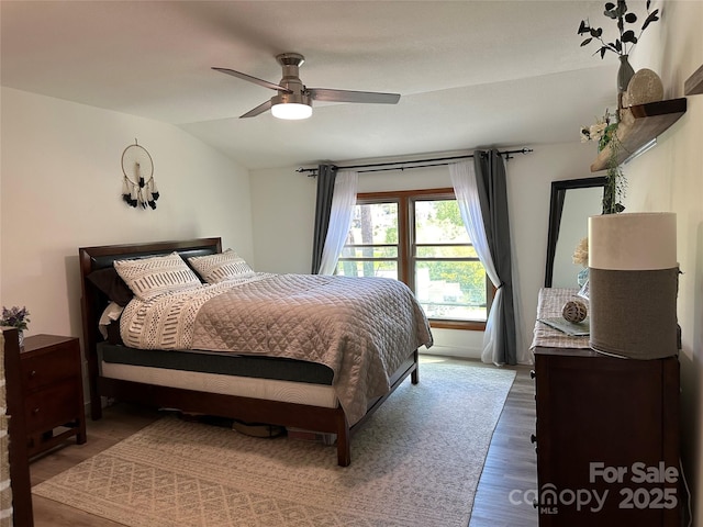 bedroom with a ceiling fan, vaulted ceiling, and wood finished floors