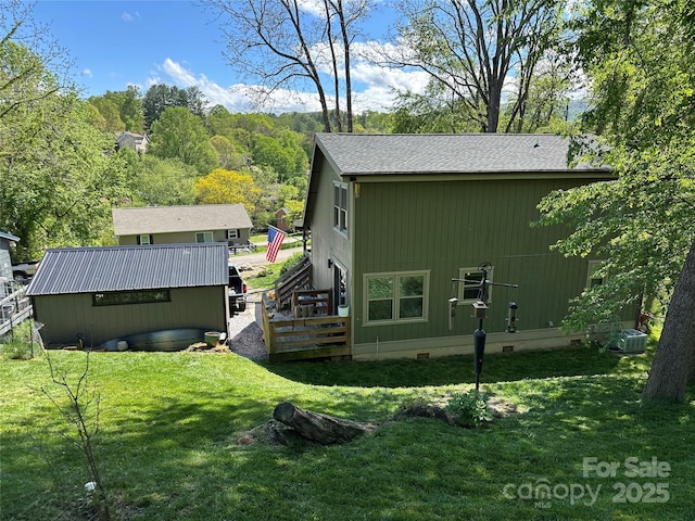 exterior space featuring a shingled roof, central AC, crawl space, a lawn, and an outdoor structure