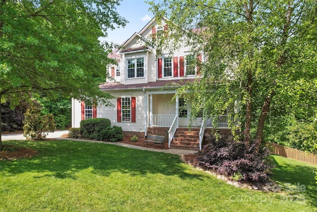 view of front of property with fence, covered porch, and a front lawn