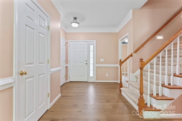 entrance foyer featuring crown molding, baseboards, stairs, and wood finished floors