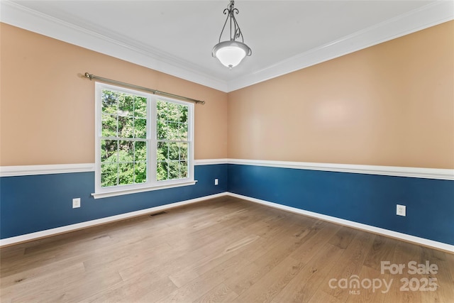unfurnished room featuring crown molding, baseboards, visible vents, and wood finished floors