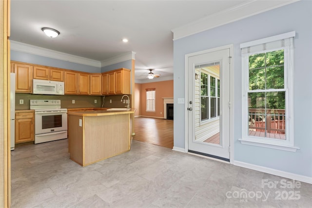 kitchen featuring crown molding, a peninsula, white appliances, a fireplace, and a ceiling fan