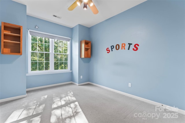 empty room with baseboards, ceiling fan, and visible vents