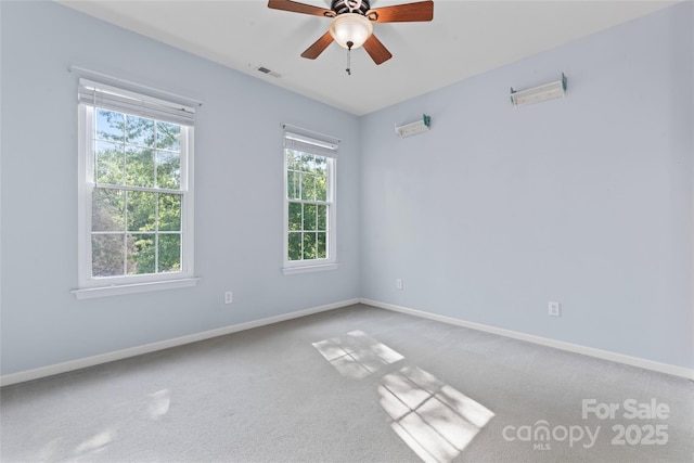 carpeted empty room featuring visible vents, a ceiling fan, and baseboards