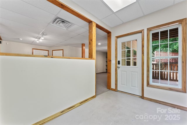 interior space featuring baseboards, visible vents, a drop ceiling, and finished concrete floors