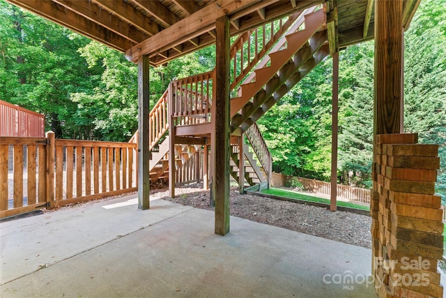 view of patio featuring fence and stairway