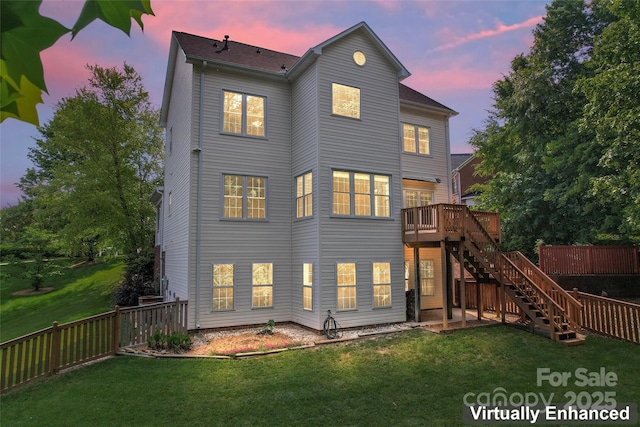 back of property at dusk with a yard, a deck, stairs, and a fenced backyard
