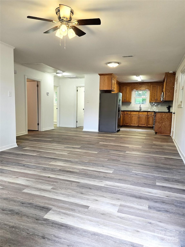 kitchen featuring ceiling fan, brown cabinetry, freestanding refrigerator, open floor plan, and visible vents