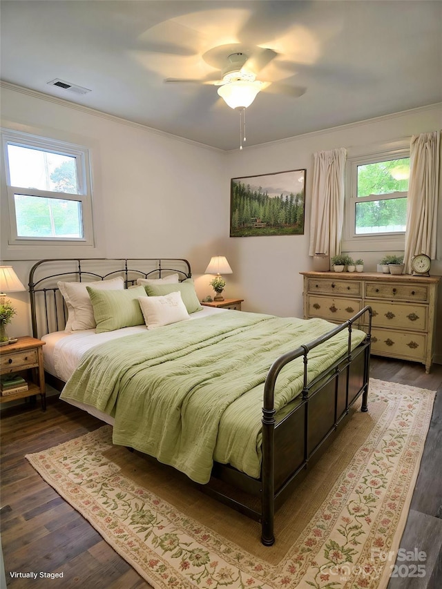 bedroom with visible vents, ornamental molding, ceiling fan, and wood finished floors