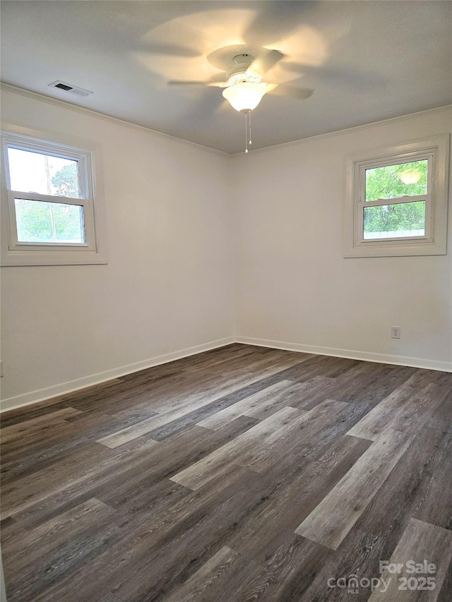 empty room featuring baseboards, a wealth of natural light, a ceiling fan, and dark wood-type flooring