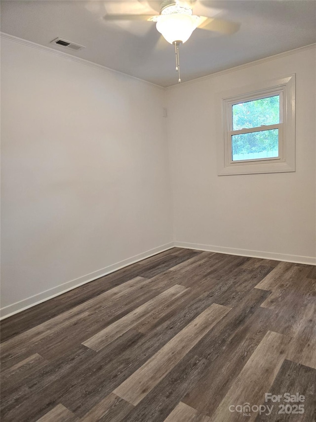 spare room with crown molding, dark wood finished floors, baseboards, and visible vents