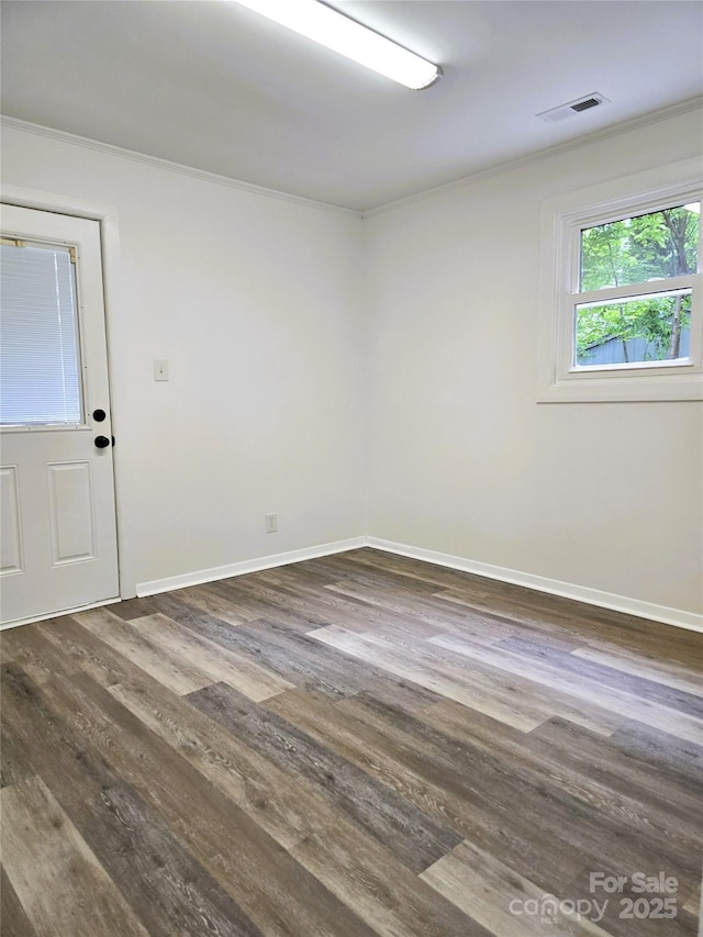 spare room with crown molding, baseboards, visible vents, and dark wood-type flooring
