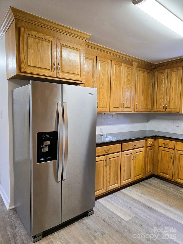 kitchen featuring dark countertops, decorative backsplash, stainless steel fridge with ice dispenser, and light wood-type flooring
