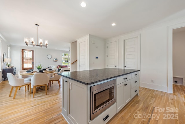 kitchen with recessed lighting, stainless steel microwave, and light wood finished floors