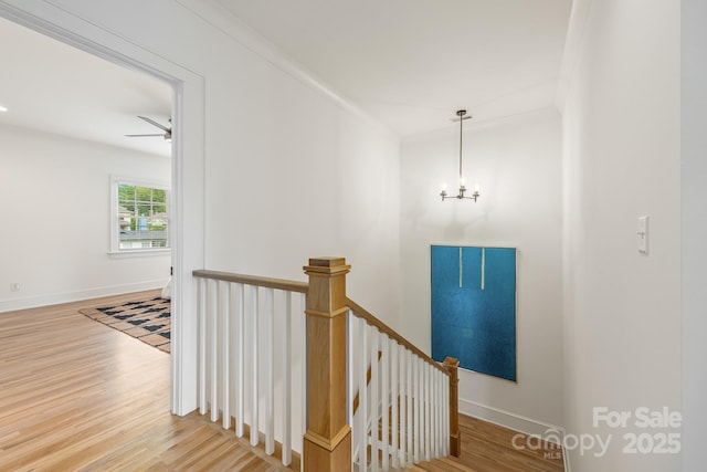 staircase with baseboards, wood finished floors, and ceiling fan with notable chandelier