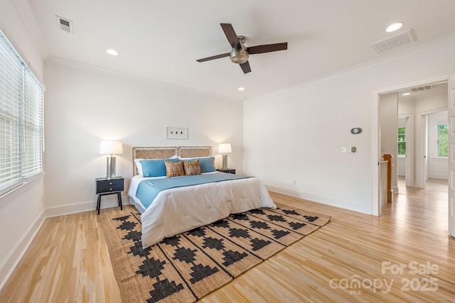 bedroom with visible vents, ornamental molding, light wood finished floors, and baseboards