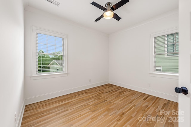 empty room featuring visible vents, crown molding, baseboards, a ceiling fan, and light wood finished floors