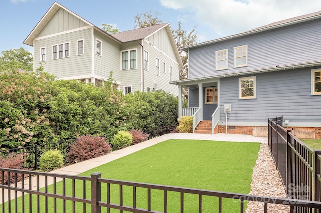 rear view of property with fence, board and batten siding, and a lawn