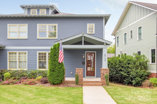 american foursquare style home with board and batten siding and a front lawn