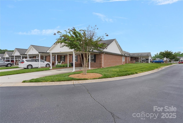 view of front of property with driveway, a front lawn, and brick siding