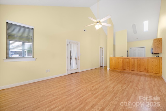 unfurnished living room with light wood-style floors, a ceiling fan, baseboards, and high vaulted ceiling