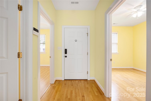 hallway featuring baseboards, visible vents, a wealth of natural light, and light wood-style floors
