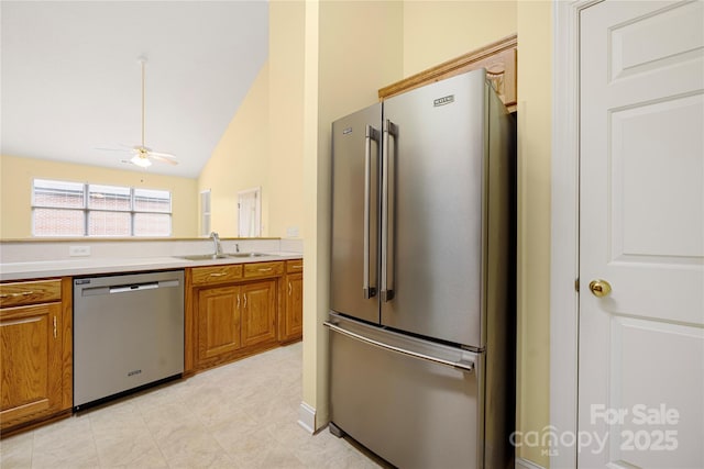 kitchen featuring vaulted ceiling, ceiling fan, stainless steel appliances, and brown cabinets