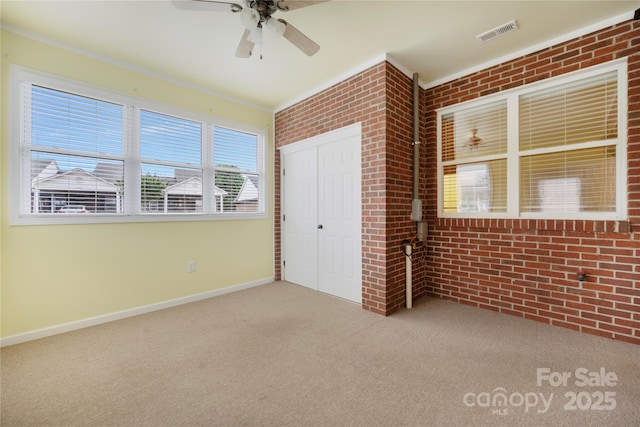 unfurnished bedroom with brick wall, visible vents, carpet, and a closet