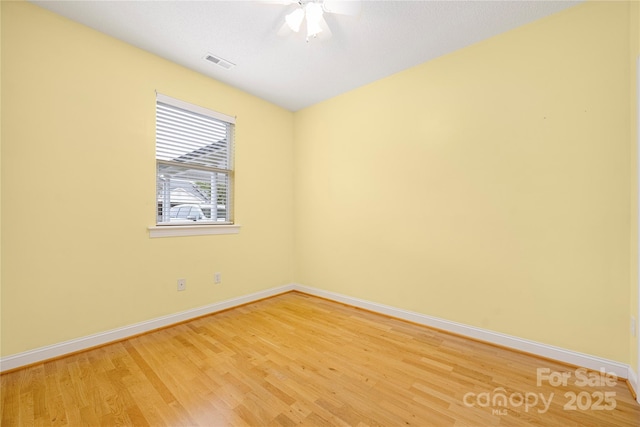 spare room with light wood-style floors, baseboards, ceiling fan, and visible vents