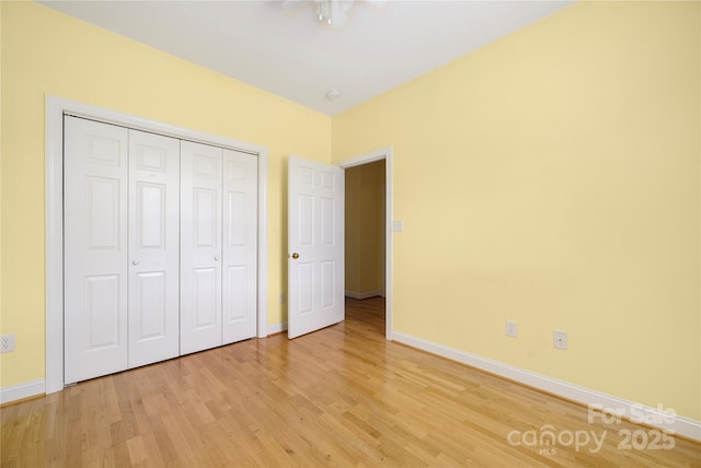 unfurnished bedroom with baseboards, light wood finished floors, and a closet