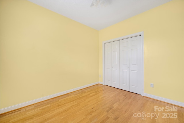 unfurnished bedroom with baseboards, a ceiling fan, a closet, and light wood-style flooring