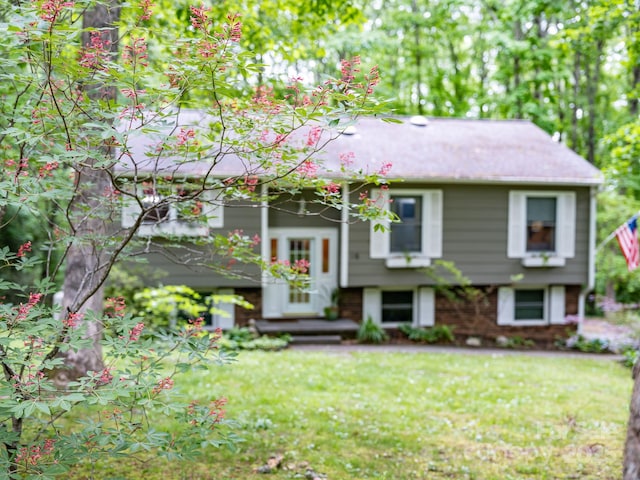 bi-level home featuring a front lawn and brick siding