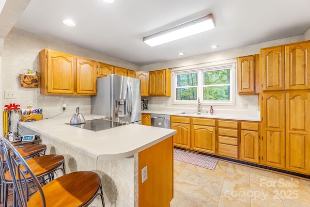 kitchen featuring stainless steel appliances, a sink, a peninsula, a breakfast bar area, and light countertops