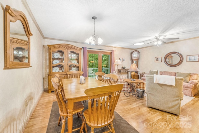 dining area featuring a textured ceiling, ornamental molding, light wood-style floors, a chandelier, and a ceiling fan