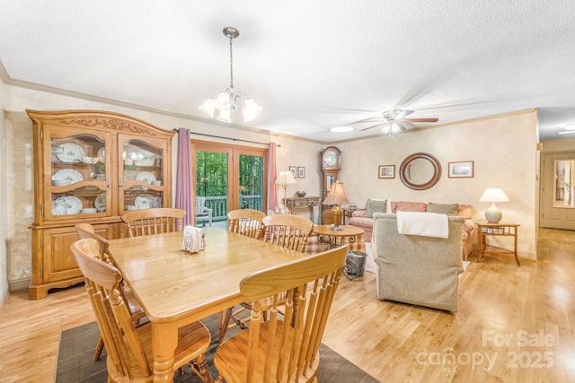dining room with a textured ceiling, light wood finished floors, a ceiling fan, a chandelier, and crown molding