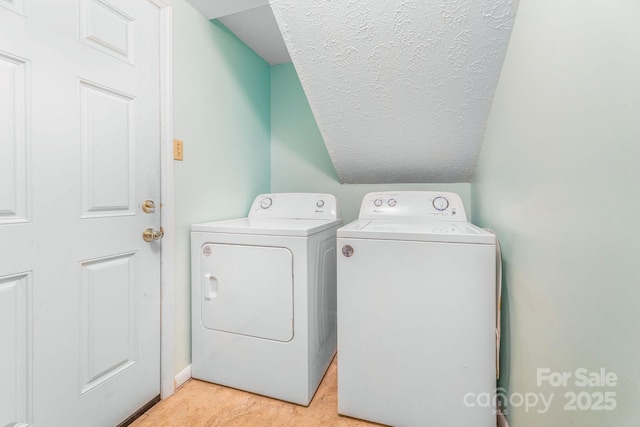 laundry area with independent washer and dryer and a textured ceiling