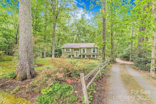 split foyer home with driveway and a forest view