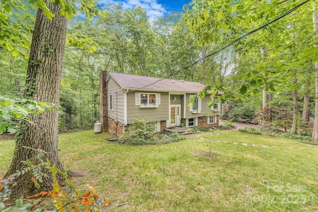 split foyer home with a front yard, a chimney, and brick siding