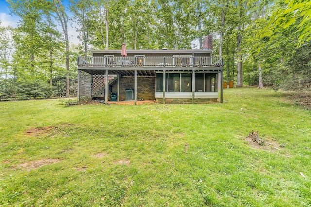 rear view of house featuring a chimney, a wooden deck, a yard, stairs, and a sunroom