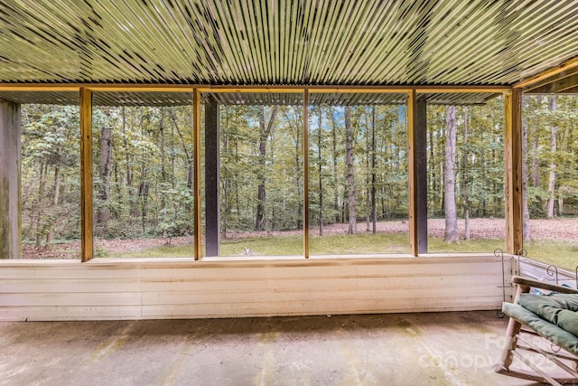 unfurnished sunroom featuring plenty of natural light and a view of trees