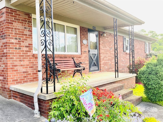 view of exterior entry featuring brick siding and covered porch