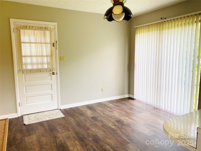 spare room featuring baseboards and dark wood-style flooring