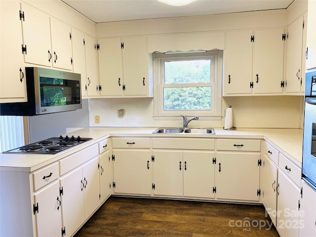 kitchen featuring dark wood-style flooring, black electric cooktop, a sink, light countertops, and stainless steel microwave