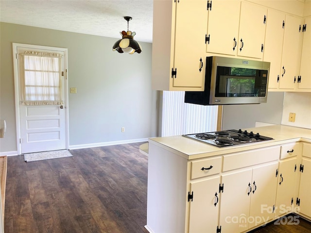 kitchen with electric stovetop, dark wood finished floors, light countertops, baseboards, and stainless steel microwave