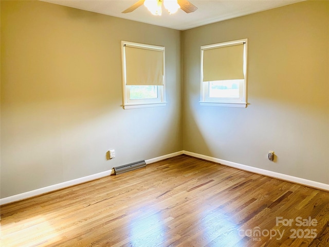 unfurnished room featuring a ceiling fan, baseboards, visible vents, and wood finished floors
