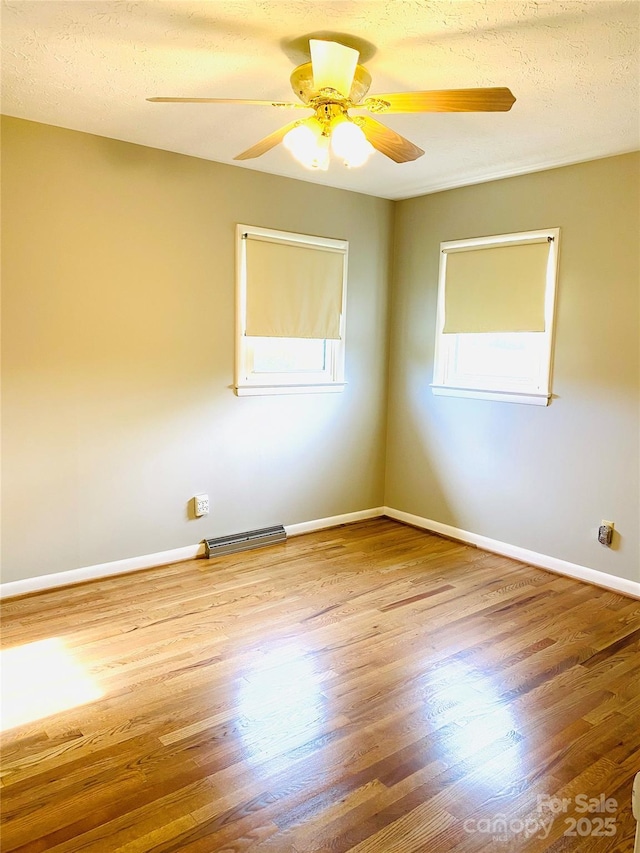unfurnished room featuring ceiling fan, baseboards, plenty of natural light, and wood finished floors
