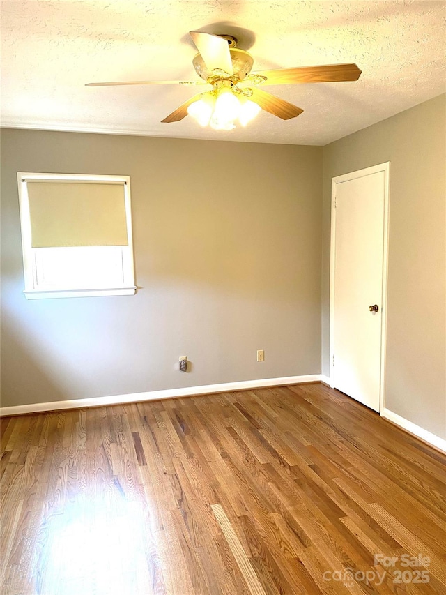 empty room with baseboards, a ceiling fan, and wood finished floors